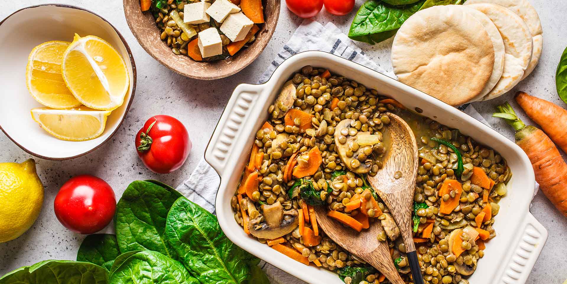 Vegan Lentil Curry in a pan surrounded by bread and various vegetables
