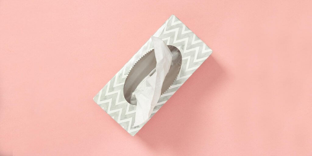 Grey and white tissue box against a pink background